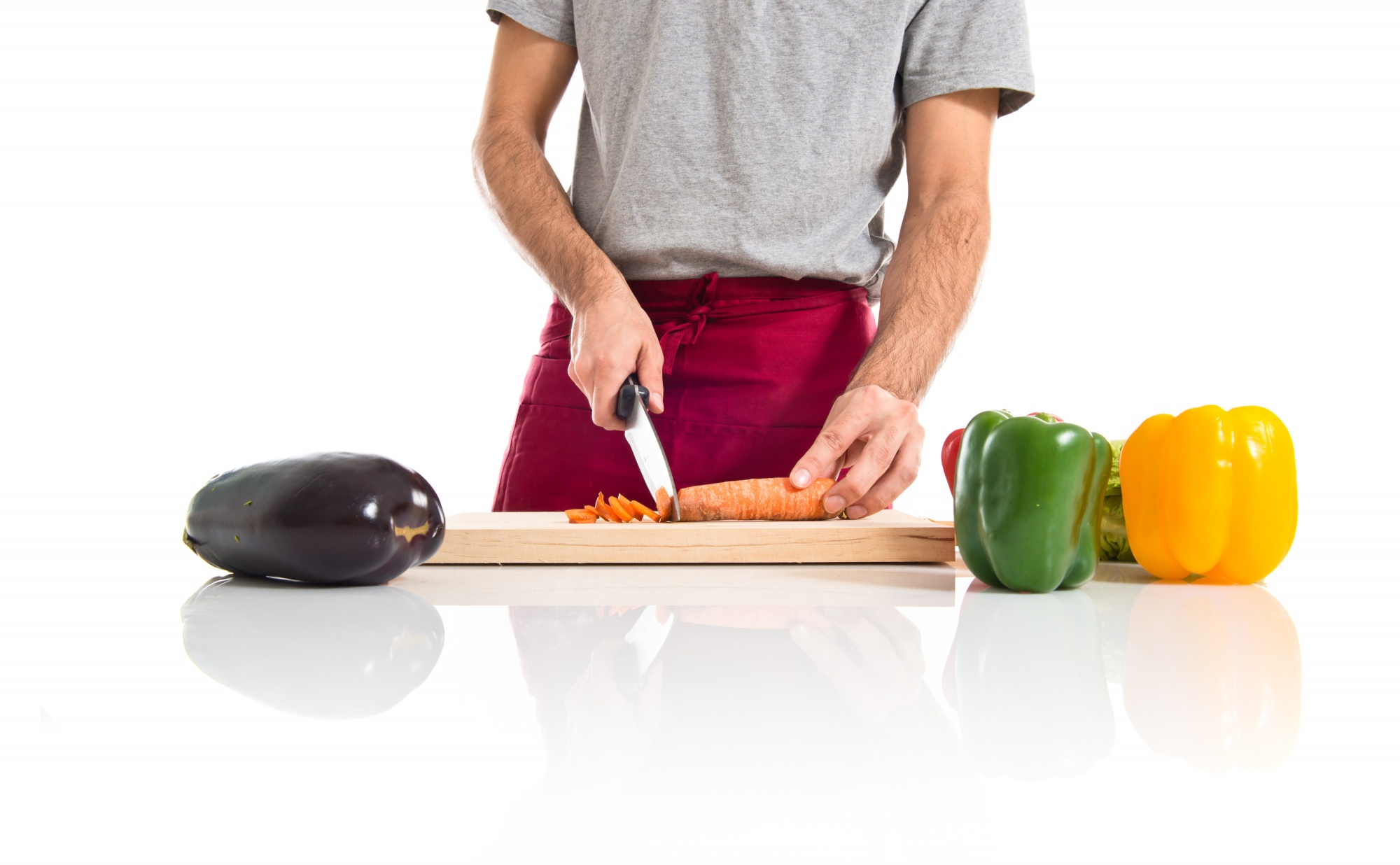 Chef che affetta verdure su tavolo di legno